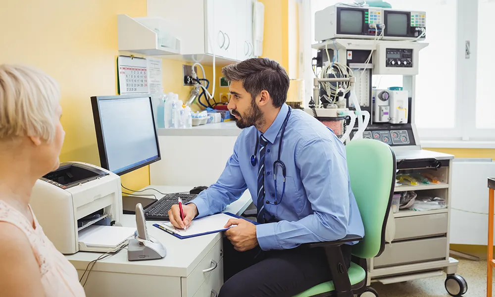 Doctor consulting a patient and uploading notes to Think Healthcare system